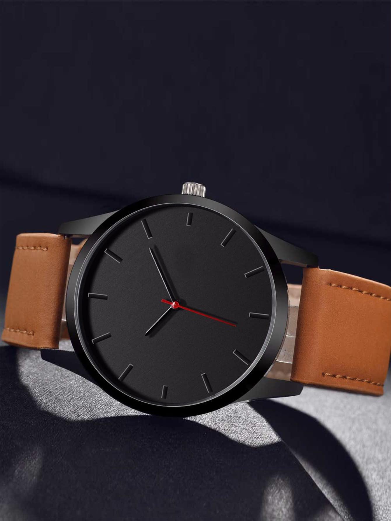 Black watch with a brown leather strap on a dark background