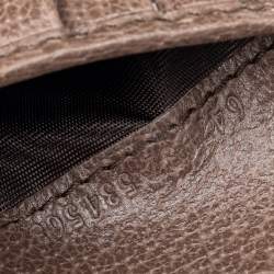 Close-up of a textured brown leather surface with a brand logo.