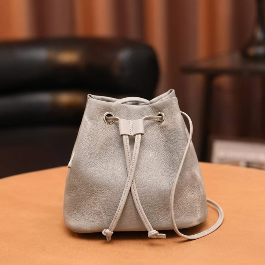 Light gray drawstring bag on a wooden surface with a blurred background