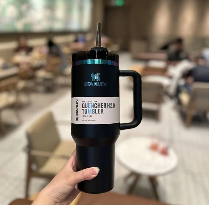 Person holding a Stanley Quencher H2O tumbler in a blurred indoor setting