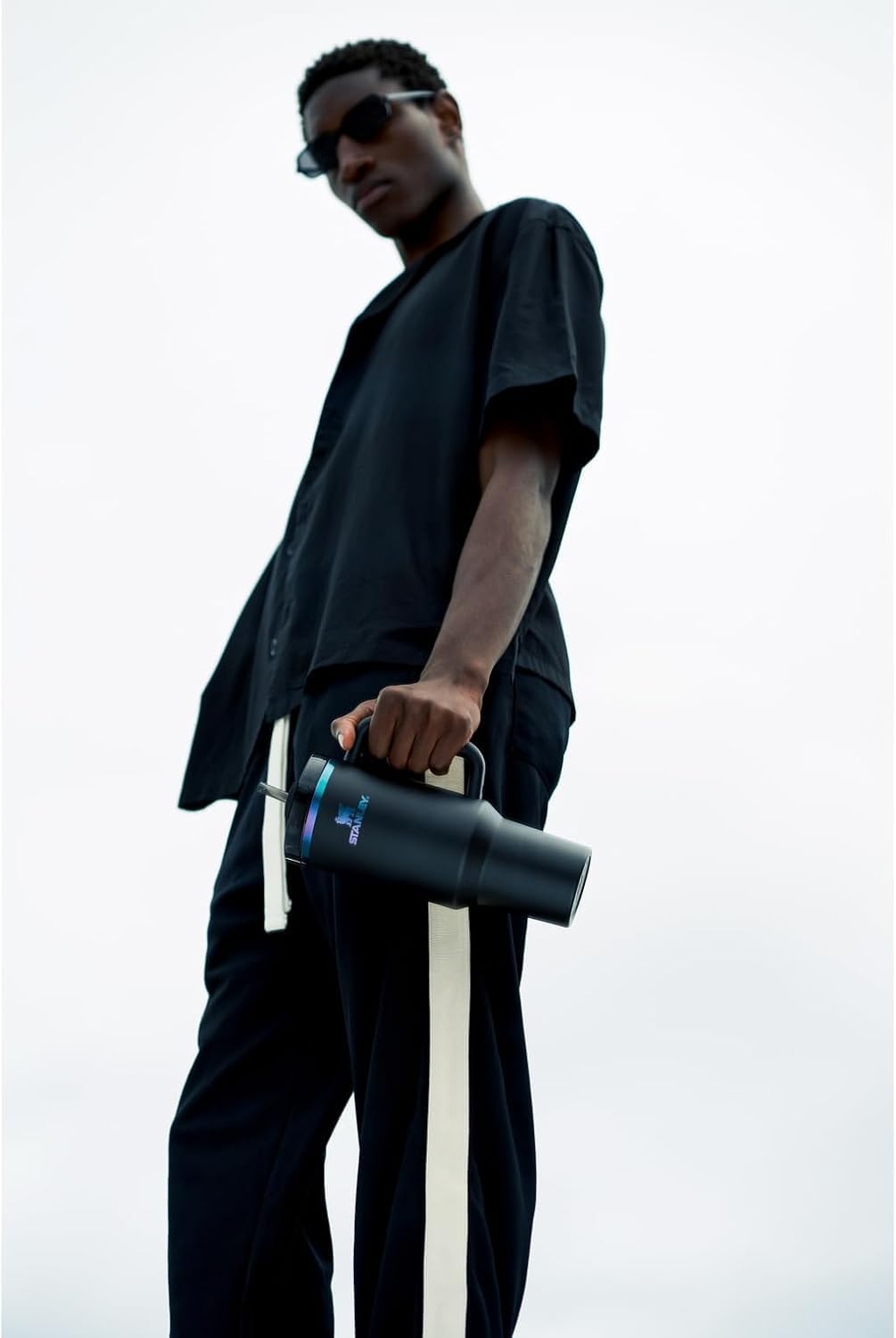 Person holding a black cylindrical object against a white background