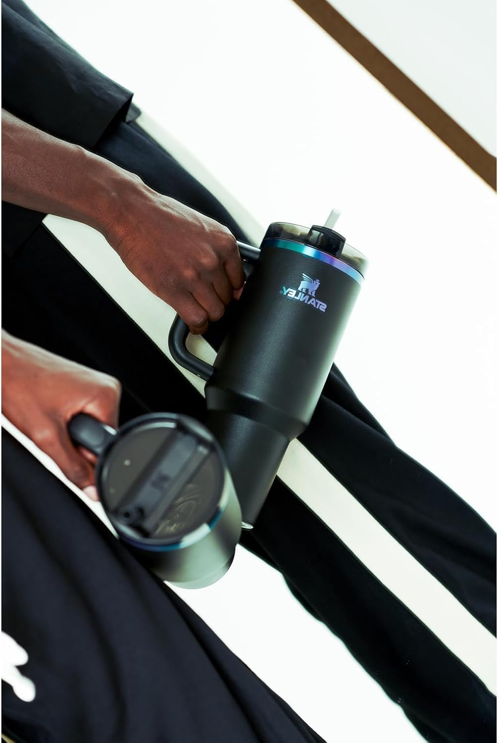 Person holding a black water bottle with a brand logo on a white background