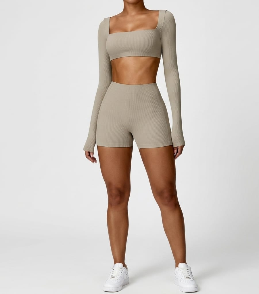 Person wearing a beige long-sleeve top and shorts set on a white background