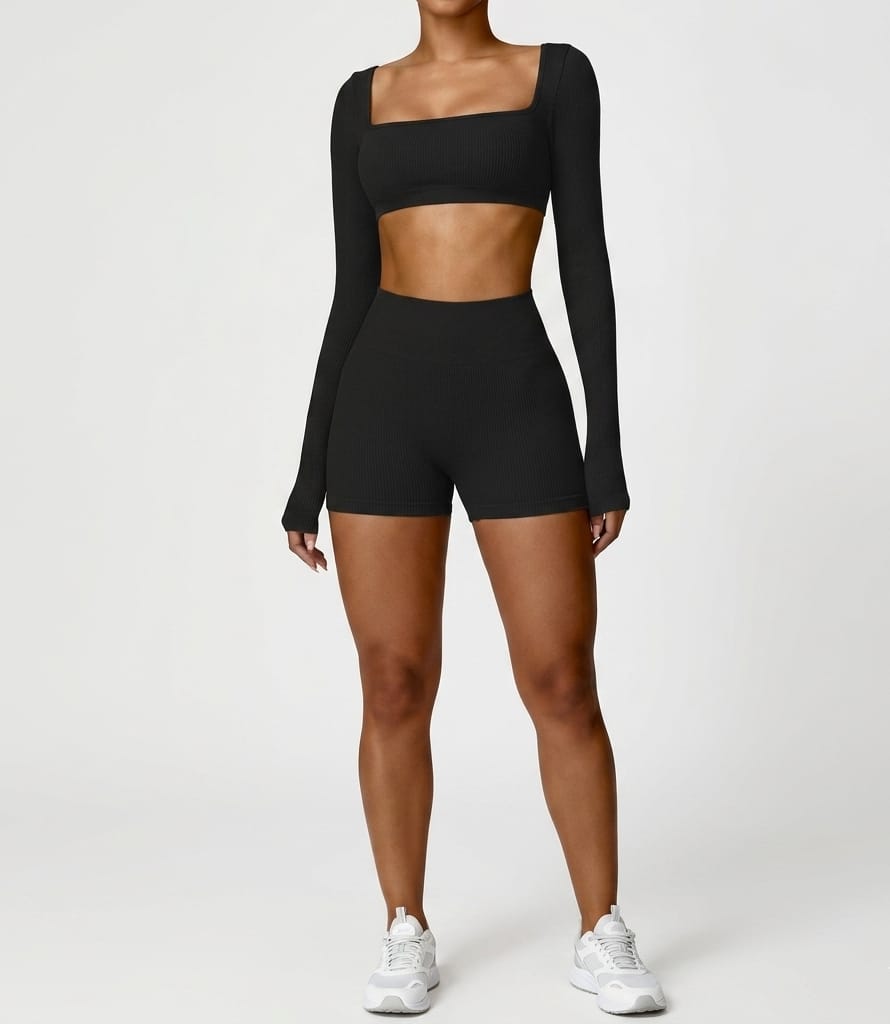 Person wearing a black long-sleeve crop top and high-waisted shorts on a white background
