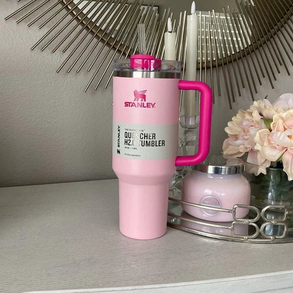 Pink Stanley tumbler with a gray label on a surface with decorative elements.