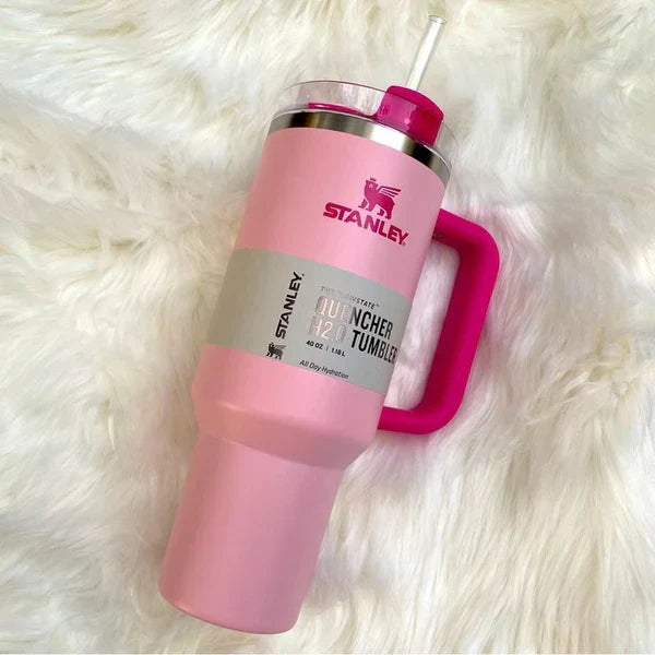 Pink Stanley tumbler with a straw on a white fluffy surface