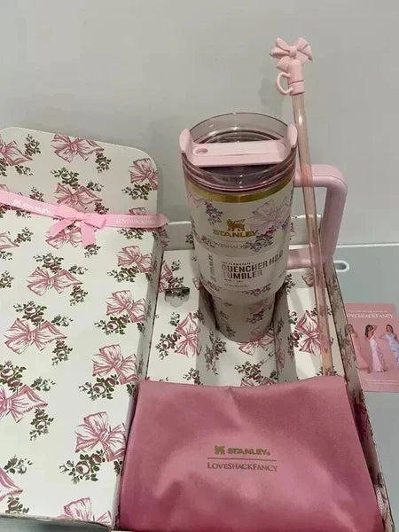 Pink Stanley tumbler with straw on a floral surface