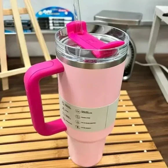 Pink insulated tumbler with a handle on a wooden surface