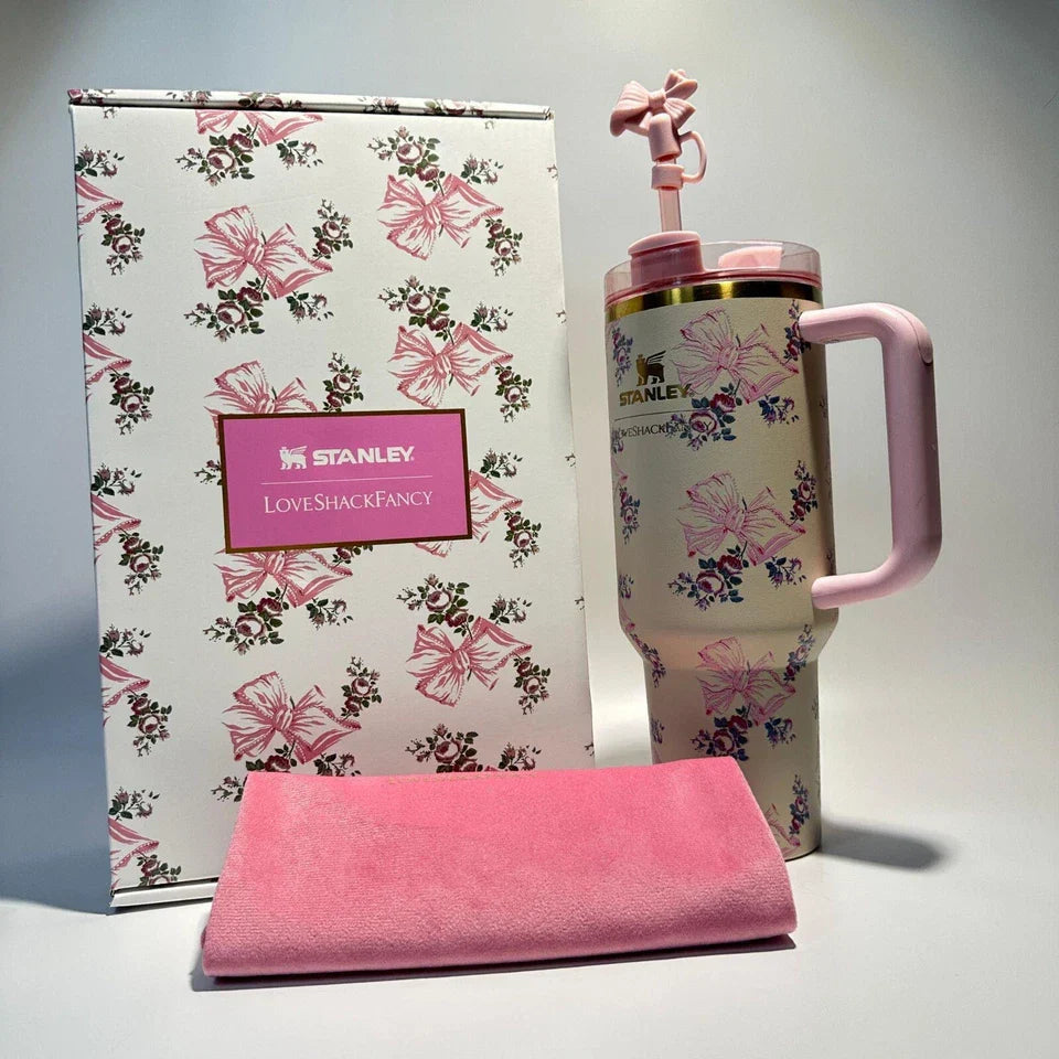 Stanley mug with floral design and pink handle, next to a matching pink towel on a gray background