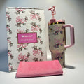 Stanley mug with floral design and pink handle, next to a matching pink towel on a gray background