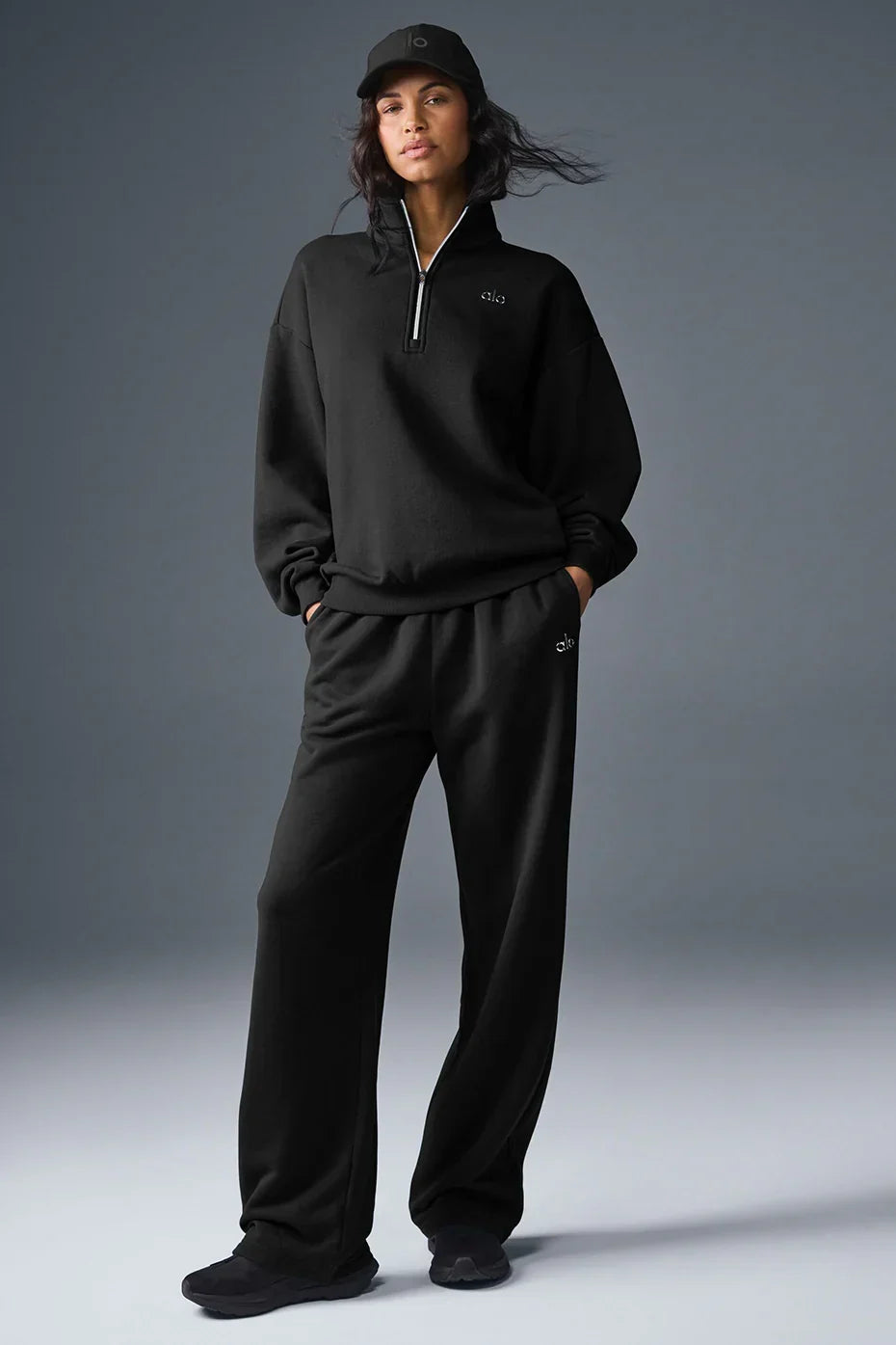 Alo Yoga Unisex Accolade Half-Zip Sweatshirt in gray with a high collar, displayed on a hanger, showcasing relaxed fit and soft fabric.