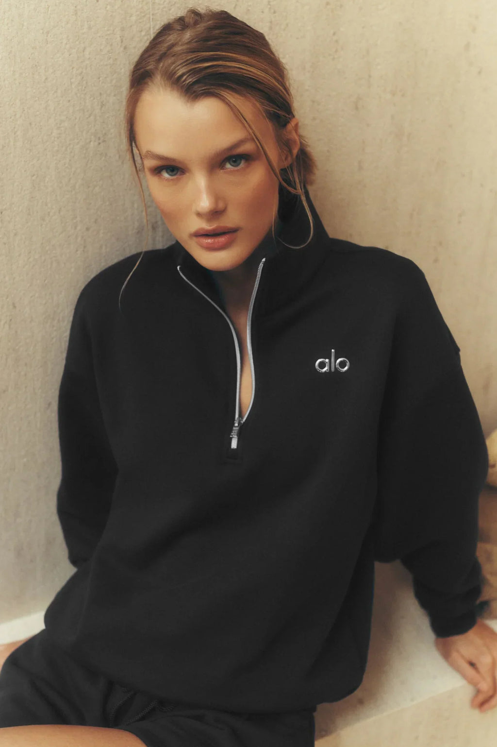 Alo Yoga unisex Accolade half-zip sweatshirt in heather gray with a high collar and relaxed fit, displayed on a hanger.