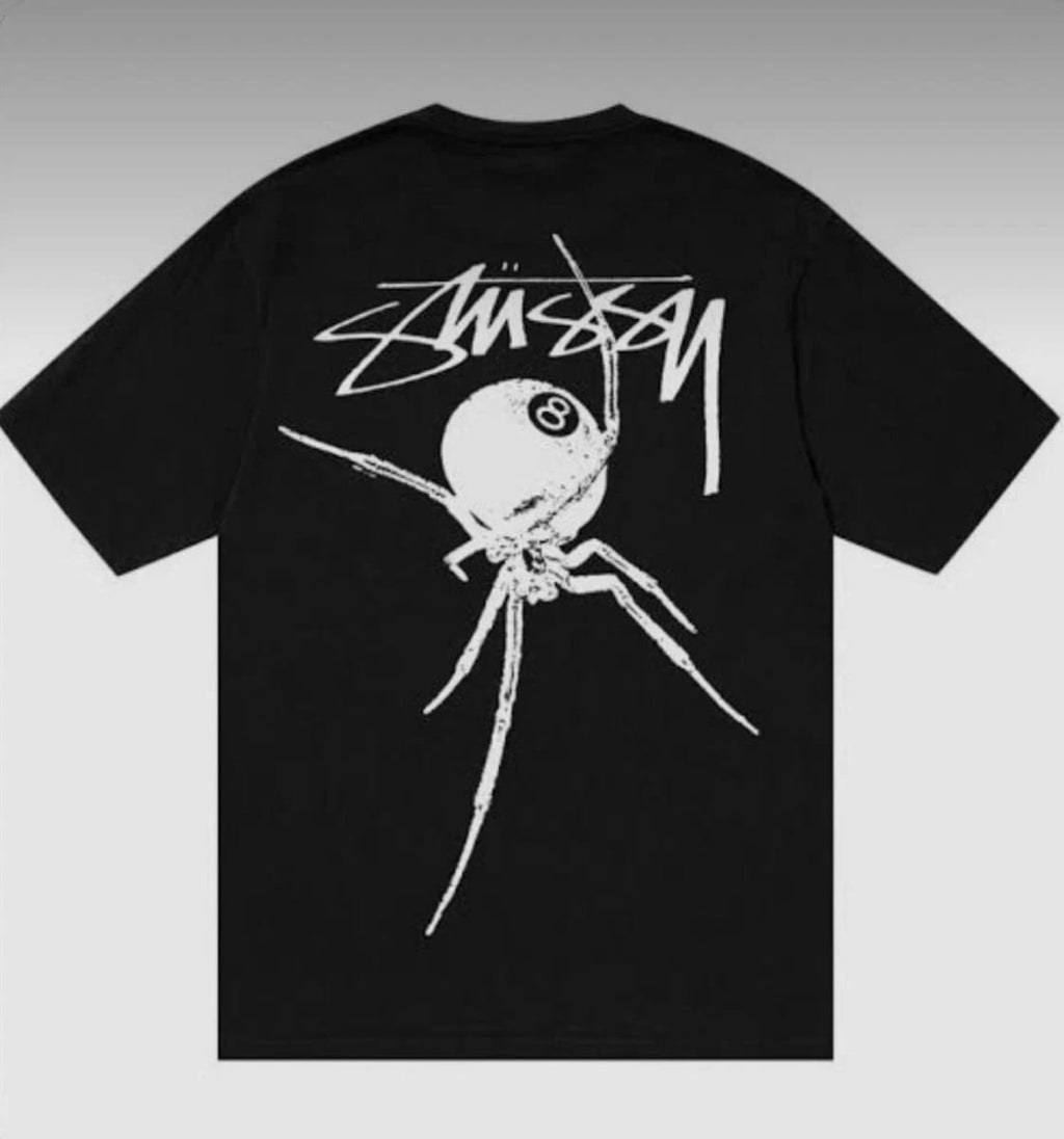Black Stussy Spider 8 Ball Tee from THE EA STORE's Essentials collection, featuring a graphic of a spider and 8 ball on the front.
